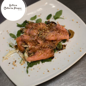 Salmone rosa nappato con croccante di granella di nocciola su letto di rucola, con riduzione di salsa e topping aromatico, riferimento al piatto napoletano di Antica Osteria Pisano
